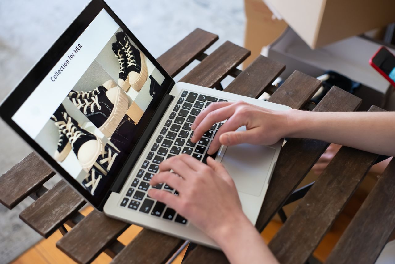 brand-02 Hands of a person browsing a Collection for HER on an online shoe store using a laptop.